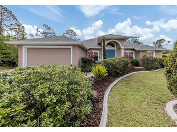 Tan house with gray roof, blue door, and landscaped yard at 4590 Oakley Rd, North Port, FL 34288