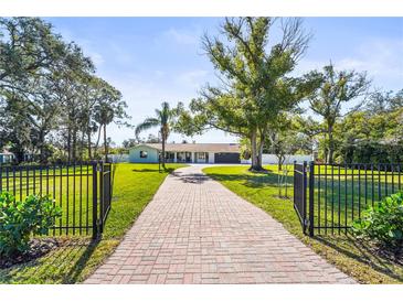 Brick driveway, lush lawn, and gated entrance enhance curb appeal at 504 68Th Avenue W Dr, Bradenton, FL 34207