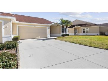 Front view of a beige house with a two-car garage and well-manicured lawn at 2608 Edgewater Ct, Palmetto, FL 34221