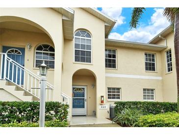 Tan two-story condo building with blue door and lush landscaping at 4250 Players Pl # 2615, Sarasota, FL 34238