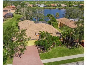 Spacious home featuring tile roof, lush landscaping, and a brick driveway, near a lake at 4850 Sweetshade Dr, Sarasota, FL 34241