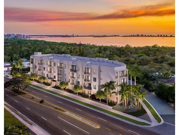 Aerial view of a modern building complex near the water at sunset at 4925 N Tamiami Trl # 208, Sarasota, FL 34234