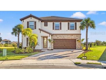 Two-story home with a brown door and attached garage, landscaping, and palm trees at 8208 Carrhill Pl, Parrish, FL 34219