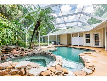 Inviting pool and spa surrounded by lush landscaping and screened enclosure at 1130 Anclote Rd Rd, Tarpon Springs, FL 34689