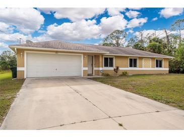 Single-story home with a white garage door and a landscaped lawn at 2415 Nowatney Ave, North Port, FL 34286