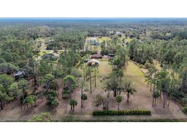 Aerial view showing a house on a spacious lot with surrounding trees and pasture at 3340 Ulman Ave, North Port, FL 34286