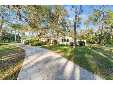 Charming single-story home featuring a lush green lawn, mature trees, and a long driveway at 3501 Sunbeam Dr, Sarasota, FL 34240