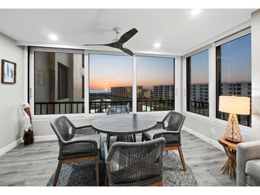 Bright dining area features floor to ceiling windows with sunset views and modern gray dining set at 5780 Midnight Pass Rd # 609, Sarasota, FL 34242