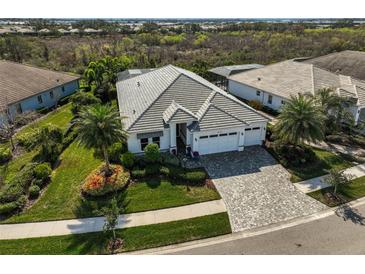 Beautiful single-story home featuring a three-car garage, lush landscaping and a tile roof at 8261 Grande Shores Dr, Sarasota, FL 34240