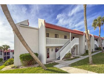 Two-story condo building with red roofs, white walls, and palm trees at 1801 Gulf N Dr # 121, Bradenton Beach, FL 34217