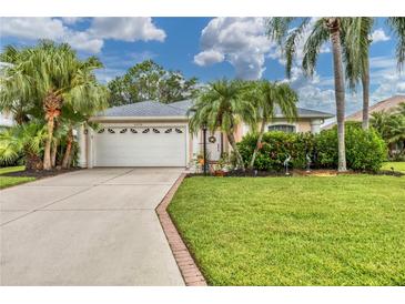 House exterior featuring a white garage door, lush landscaping, and palm trees at 6650 Cheswick St, Sarasota, FL 34243