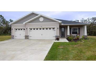 Two-car garage, covered porch, and landscaped lawn at 6614 162Nd E Pl, Parrish, FL 34219