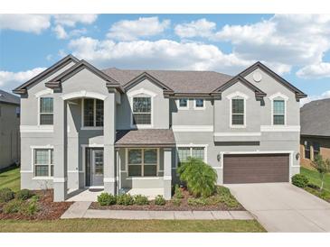 Two-story house with gray siding, brown garage door, and landscaping at 12985 Bliss Loop, Bradenton, FL 34211