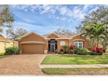 Charming single-story home with well-manicured lawn and brick driveway, lovely landscaping and a beautiful blue sky at 5171 51St W Ln, Bradenton, FL 34210