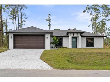 Newly constructed home with a modern design, featuring a two-car garage and a landscaped lawn at 5270 Adina Cir, North Port, FL 34291