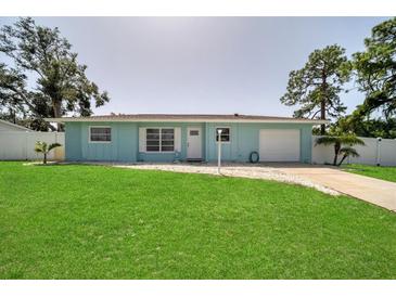 Ranch style home with a light blue exterior, spacious lawn and attached garage at 881 Polaris Rd, Venice, FL 34293