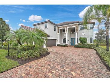 Stately home with brick drive, lush landscaping, and a striking blue entry door at 13408 Swiftwater Way, Bradenton, FL 34211