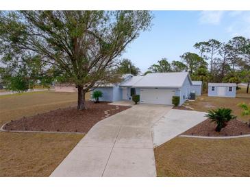 Cute light blue house with a large tree and long driveway at 15026 Dania Ave, Port Charlotte, FL 33953