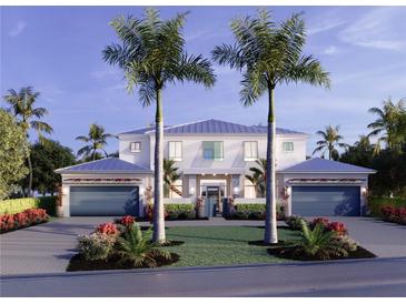Two-story home with double garages, lush landscaping, and palm trees at 1521 S Lake Shore Dr, Sarasota, FL 34231