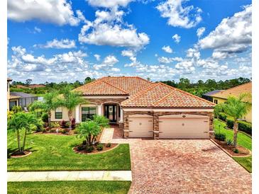 Luxury home with a tile roof, landscaped yard, and brick driveway at 20686 Valprato Ct, Venice, FL 34293