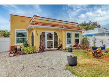 Charming yellow house with a tile roof, landscaping, and a gravel driveway at 305 Pameto Rd, Nokomis, FL 34275