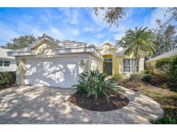 Charming yellow house with a white garage door and landscaped yard at 554 Fallbrook Dr, Venice, FL 34292