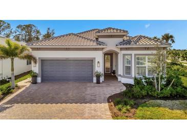 One-story home with gray garage doors, paver driveway, and lush landscaping at 10201 Beach Dune Dr, Englewood, FL 34223