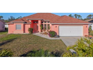 Attractive coral home with a two-car garage and well-manicured lawn at 2421 Palomar St, North Port, FL 34287