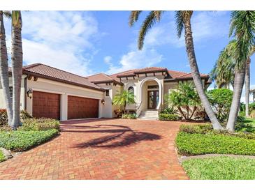 Luxury home with three-car garage, brick driveway, and lush landscaping at 4110 Commodore Blvd, Cortez, FL 34215