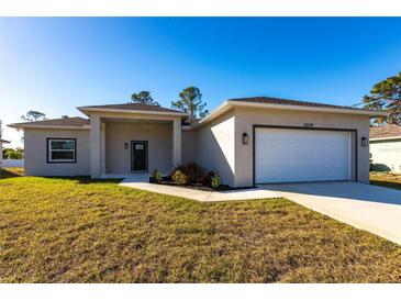 New construction home with a landscaped lawn and attached garage at 5534 Fairlane Dr, North Port, FL 34288