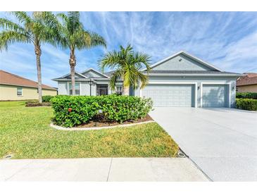 Single-story home with two-car garage, landscaping, and palm trees at 12904 49Th E Ln, Parrish, FL 34219