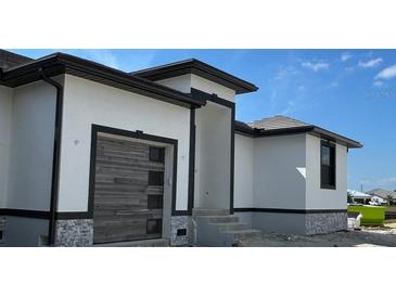 Modern home exterior with dark trim, wood garage door, and tile accents at 1327 Wesley Dr, Punta Gorda, FL 33950