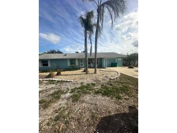 Light teal single-story home with palm trees and a landscaped yard at 211 84Th St, Holmes Beach, FL 34217