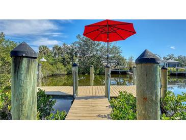 Private wooden dock with red umbrella, offering waterfront access at 603 Barnes Pkwy, Nokomis, FL 34275