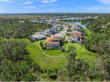 Aerial view of a house and surrounding community with a large backyard at 6229 Rivo Lakes Blvd, Sarasota, FL 34241