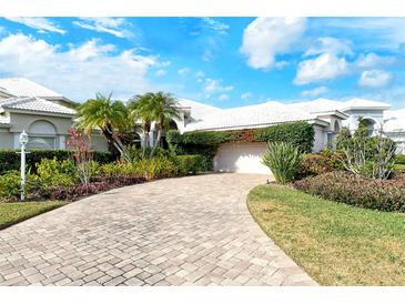 House exterior featuring a brick driveway, lush landscaping, and a two-car garage at 6790 Paseo Castille, Sarasota, FL 34238