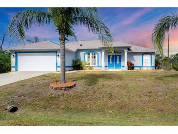 Charming single-story home with a two-car garage, vibrant blue trim and beautiful tropical landscaping at 2926 Sultan Ct, North Port, FL 34286