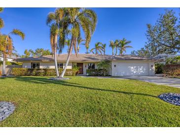 Single-story home with a tile roof, landscaped lawn, and palm trees at 419 Partridge Cir, Sarasota, FL 34236