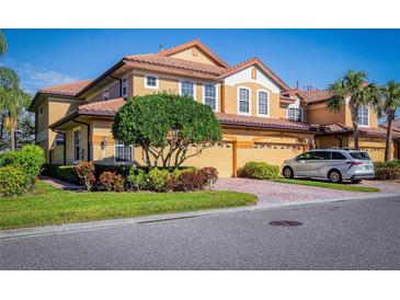 Tan two-story home with two-car garage, lush landscaping, and a paved driveway at 8368 Miramar Way # 21, Lakewood Ranch, FL 34202