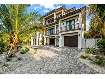 Luxury home with palm trees, driveway, and attached garage at 107 Maple Ave, Anna Maria, FL 34216