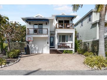 Two-story home with a white exterior, blue accents, and a paved driveway at 110 46Th St, Holmes Beach, FL 34217