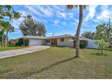 Tan single-story house with a curved driveway, attached garage, and lush lawn at 372 Tihami Rd, Venice, FL 34293