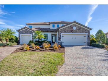 Two-story house with stone accents, three-car garage, and landscaped yard at 6868 Wild Lake Ter, Bradenton, FL 34212