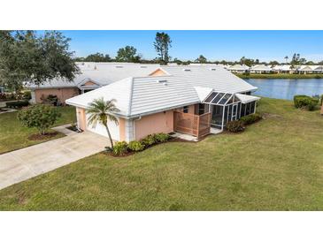 Exterior view of charming villa with lake access, lush landscaping, and attached garage at 713 Harrington Lake N Dr # 18, Venice, FL 34293