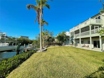 Expansive waterfront backyard with lush green lawn, private dock, and multi-story home with balconies at 115 Burns Rd, Terra Ceia, FL 34250