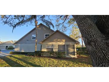 Tan house with green lawn, large tree, and some shrubs at 3401 Rochelle Ct # 131, Clearwater, FL 33761