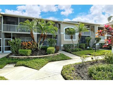 Exterior view of condo building with lush landscaping and walkway at 5211 Mahogany Run Ave # 124, Sarasota, FL 34241