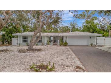 Single-story home with white exterior, paved driveway, and mature landscaping at 567 Venice Ln, Sarasota, FL 34242