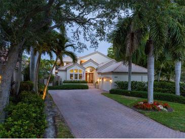 Two-story house with brick driveway, lush landscaping, and a three-car garage at 601 Weston Pointe Ct, Longboat Key, FL 34228