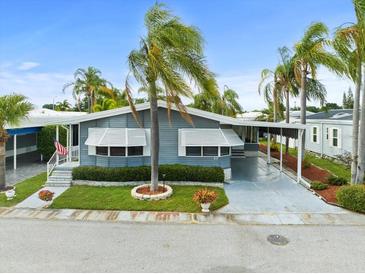 Gray manufactured home with carport, landscaping, and American flag at 62 Pelican S Dr, Oldsmar, FL 34677